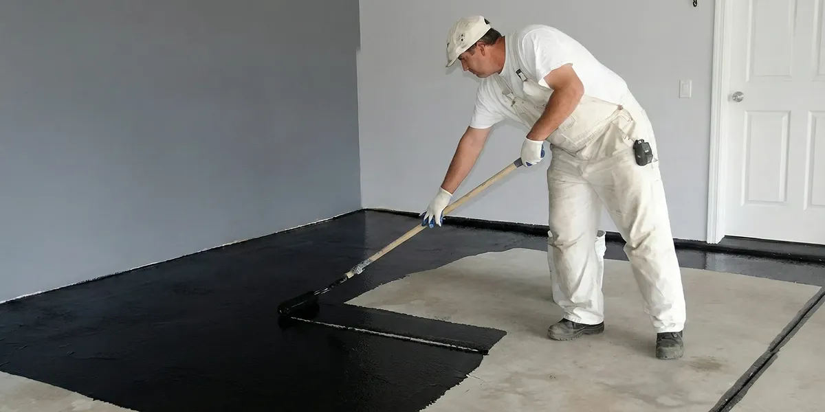 basement waterproofing professional applying waterproof coating to protect a basement floor in Fort Wayne, IN